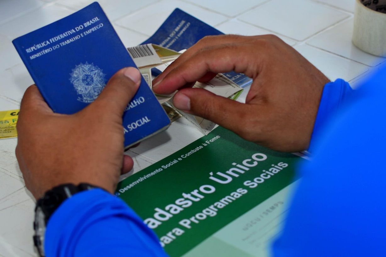 Homem usuário dos serviços do CRAS com a Carteira de Trabalho nas mãos com logo do Cadastro Único