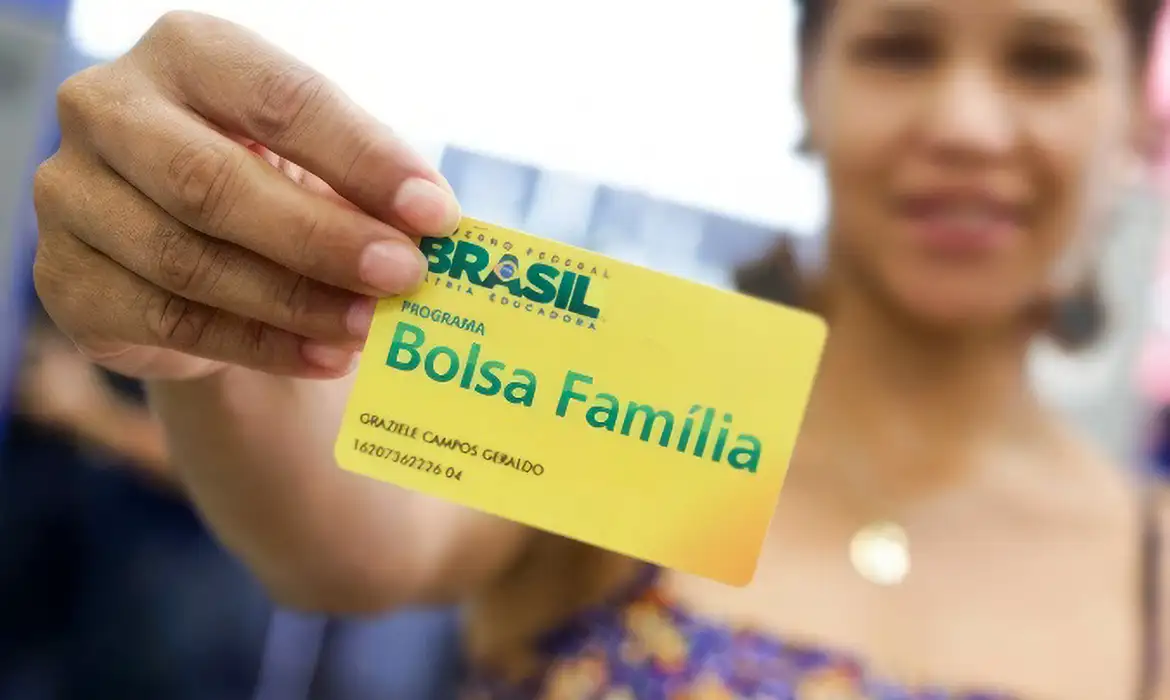 Imagem de uma pessoa sozinha do bolsa família mostrando o cartão do programa