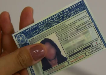 Imagem de uma mão feminina segurando uma CNH.