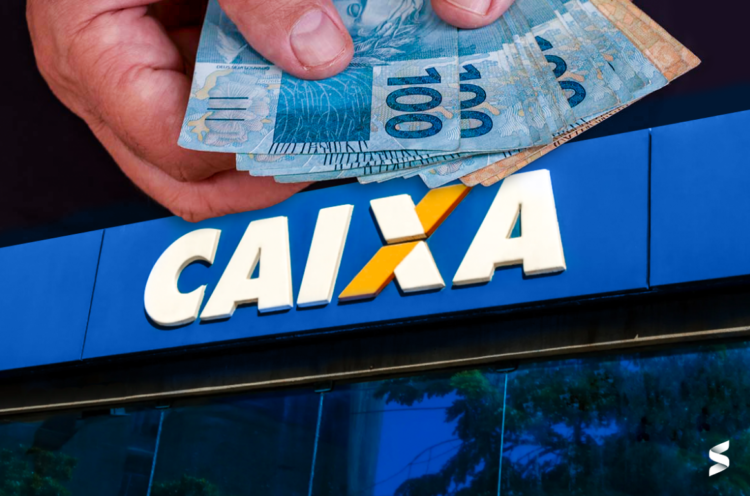 Mão segurando notas de reais em frente a uma agência da Caixa Econômica Federal.