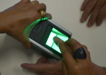 Pessoa usando biometria digital, exemplificando o processo de verificação para o Bolsa Família.