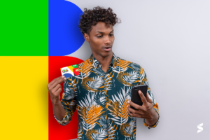  Homem segurando um cartão do Bolsa Família e olhando para o celular com expressão surpresa.