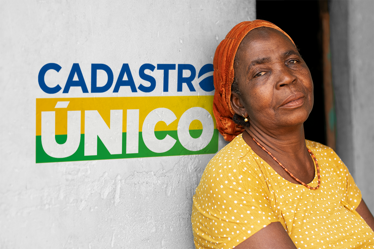 Mulher com camiseta amarela em frente a uma parede com o logo do Cadastro Único.