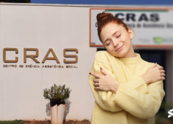 Mulher sorrindo e se abraçando em frente ao prédio do CRAS, simbolizando acolhimento e apoio social.