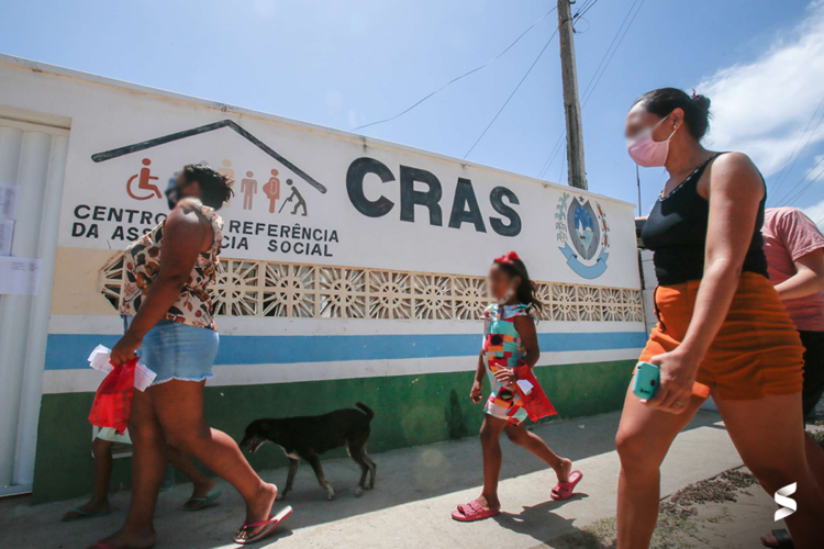 Pessoas caminhando em frente ao CRAS para mutirão de atualização do Cadastro Único