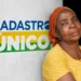 Mulher em frente a uma parede com a logo do Cadastro Único