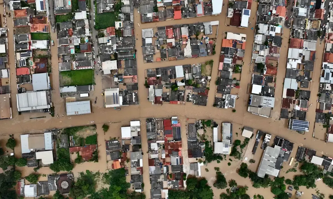 Vista aérea de uma área afetada por inundação, destacando os danos causados por desastres climáticos.