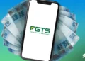 Celular exibindo o logo do FGTS com notas de 100 reais ao fundo, representando o saque-aniversário de 2025.
