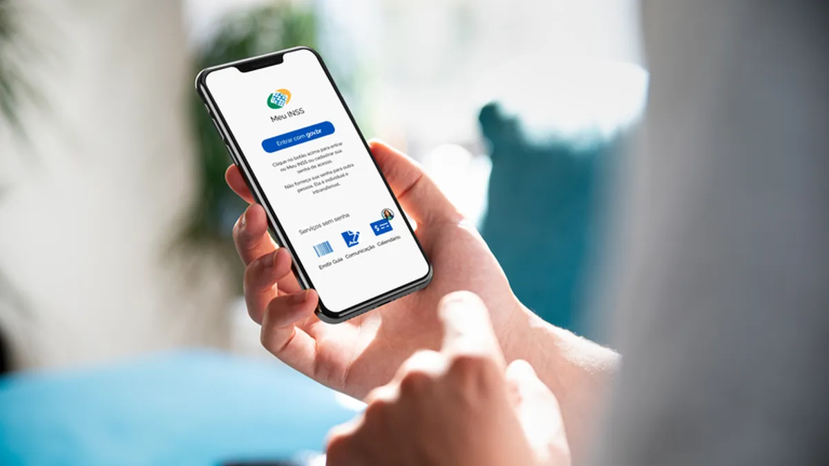 Pessoa segurando um celular com o aplicativo Meu INSS aberto na tela.