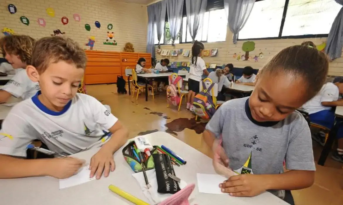 Crianças na sala de aula da educação infantil, desenvolvendo atividades escolares.