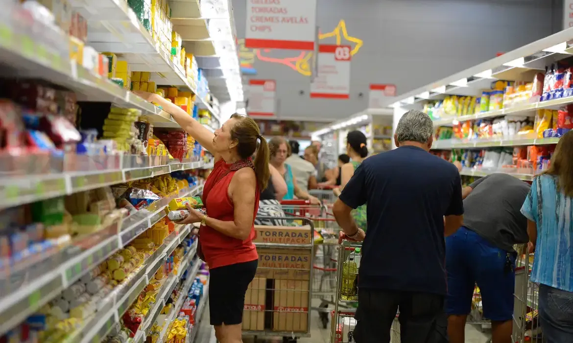 Consumidores fazendo compras em um supermercado movimentado.