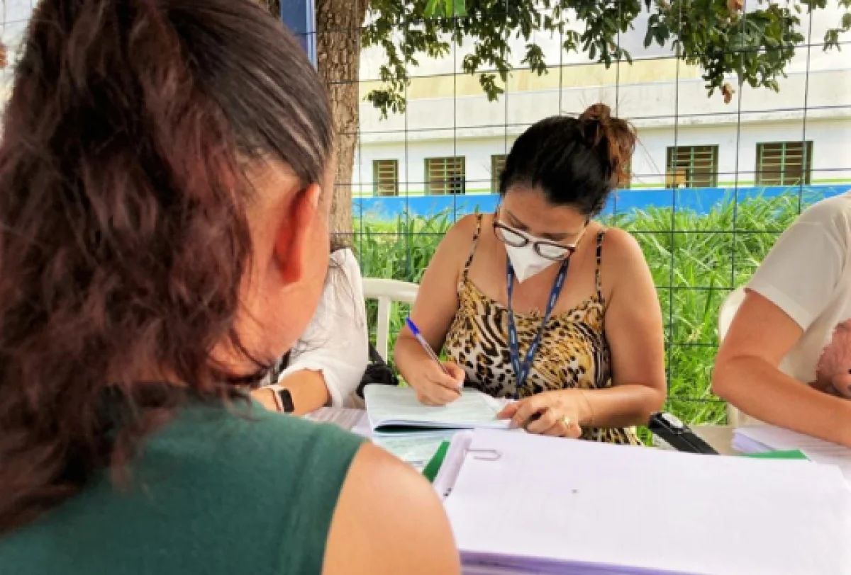 Pessoa preenchendo um formulário durante o processo de inscrição e atualização do CadÚnico, com documentos em mesa.