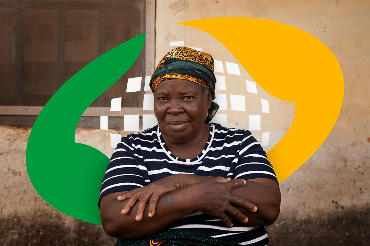 Mulher com blusa listrada, sorrindo e com os braços cruzados, com o logo do Cadastro Único ao fundo.