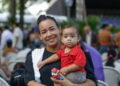 Mãe sorridente segurando seu filho durante evento do programa Mães de Pernambuco