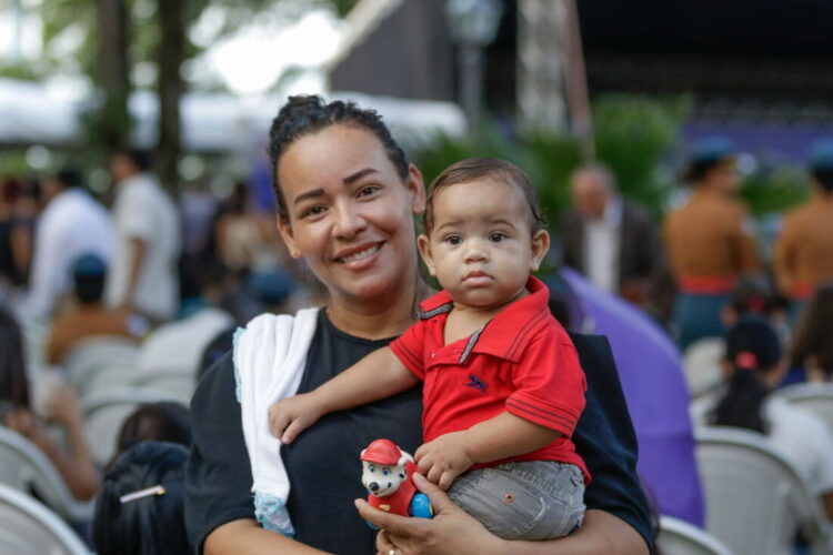 Mãe sorridente segurando seu filho durante evento do programa Mães de Pernambuco