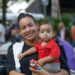 Mãe sorridente segurando seu filho durante evento do programa Mães de Pernambuco