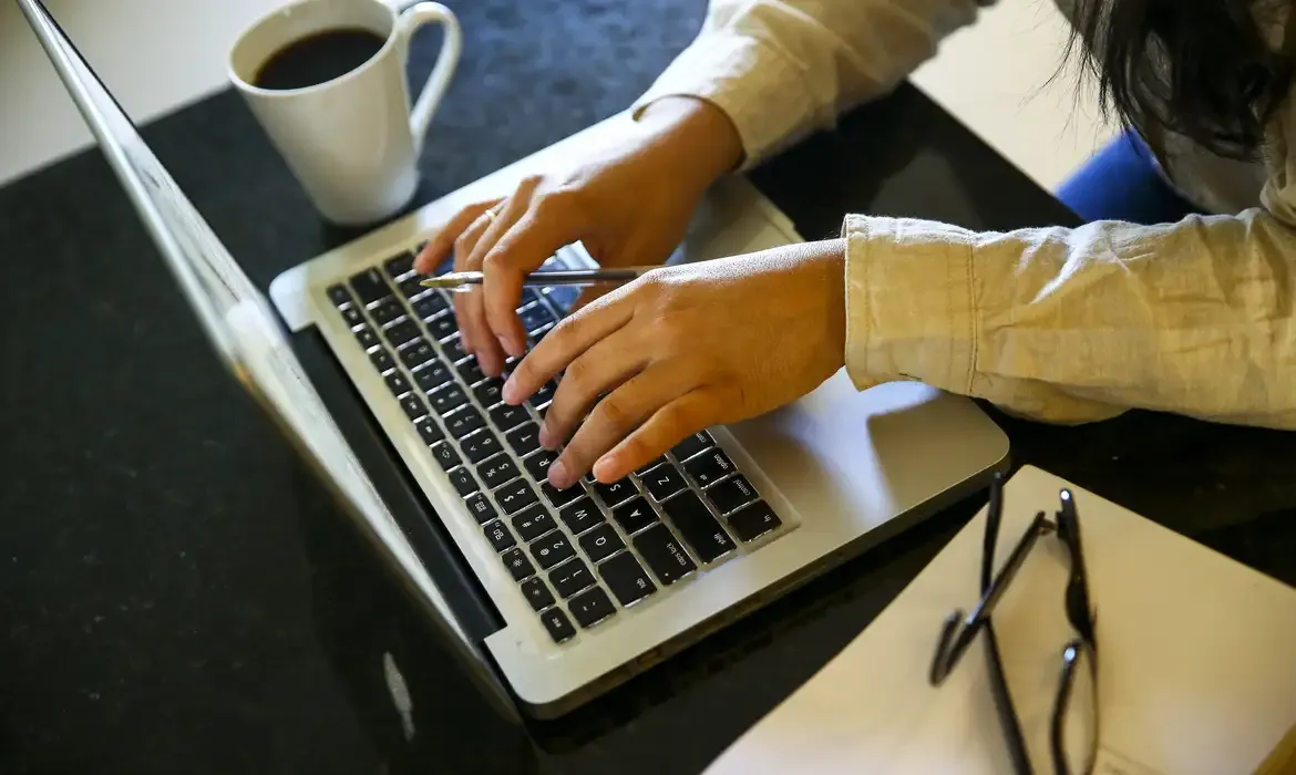 Pessoa digitando em um notebook, representando a inscrição na instituição de ensino superior e o cadastro na Plataforma Freire.