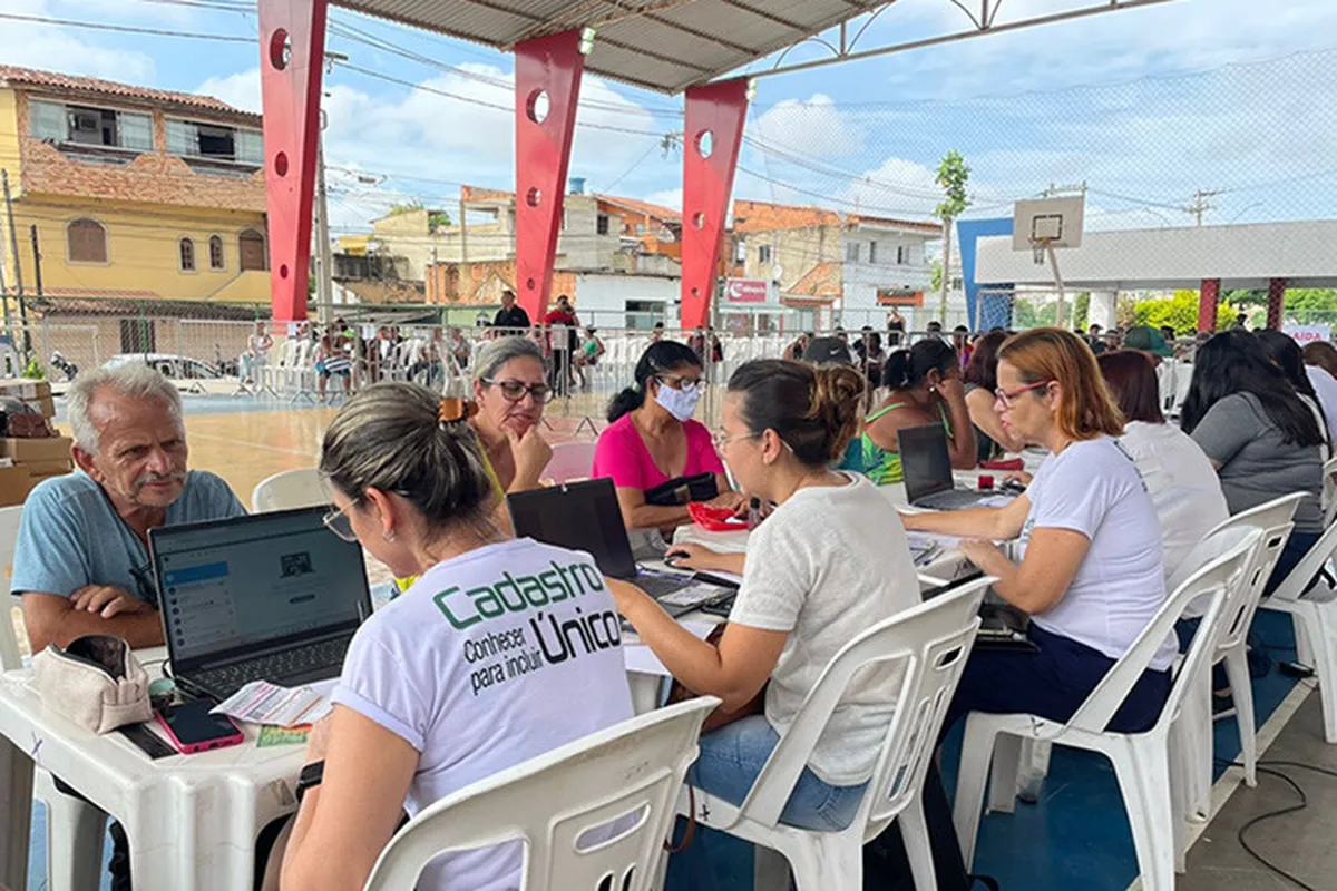 Mutirão de atualização do Cadastro Único sendo realizado em uma quadra coberta com atendentes e cidadãos