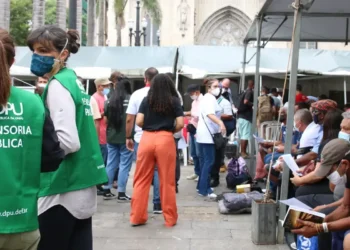 Defensoria Pública e pessoas participando de um mutirão, representando o processo de inscrição para o programa.