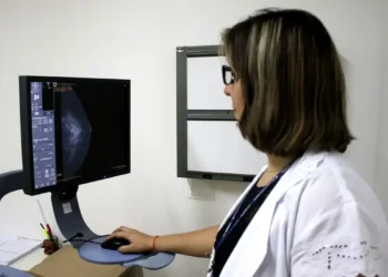 Médica analisando exame de mamografia em um computador, representando campanha de exames gratuitos.