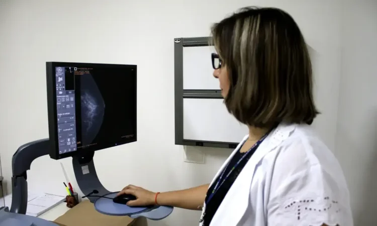 Médica analisando exame de mamografia em um computador, representando campanha de exames gratuitos.