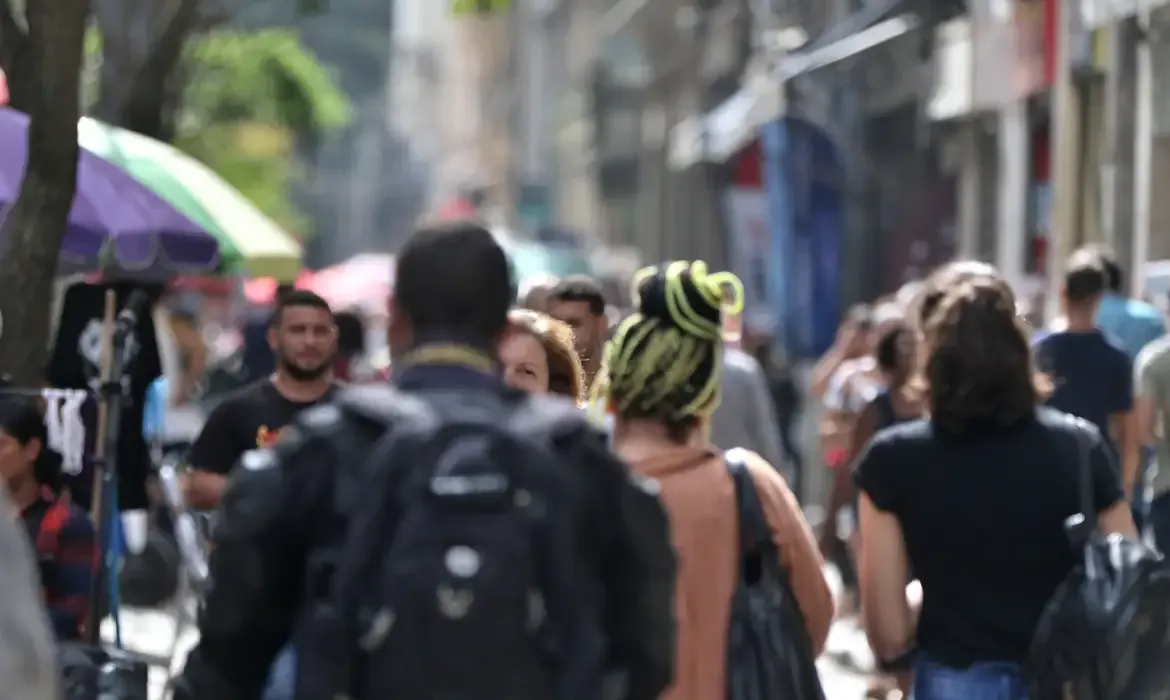 Movimento de pessoas em uma rua comercial durante o dia.