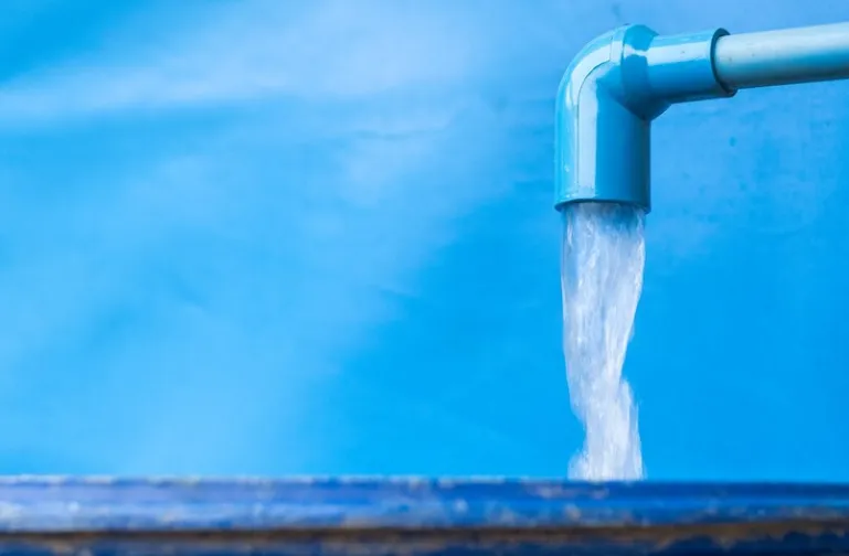 Fluxo de água sendo despejado de um tubo azul, representando a solução para problemas de escassez de água.