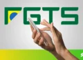 Mãos segurando um smartphone com o logo do FGTS ao fundo, representando o saque-aniversário de 2025.