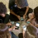 Estudantes usando celulares no ambiente escolar durante o intervalo, representando o debate sobre o uso de dispositivos móveis nas escolas.