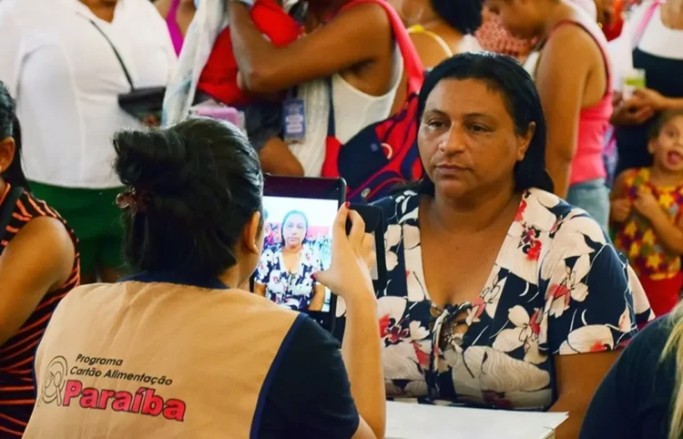 Mulher sendo fotografada durante o processo de atualização do Cartão Alimentação no programa da Paraíba.