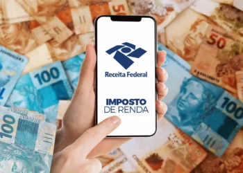 Pessoa acessando a Receita Federal no celular, com o logo do Imposto de Renda 2025 ao fundo e cédulas de dinheiro.