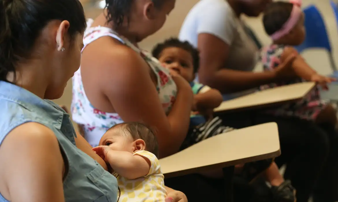 Mães solo amamentando e cuidando de seus filhos em um ambiente comunitário.