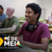 Estudante sorridente em sala de aula com fones no pescoço, representando o programa Pé-de-Meia.