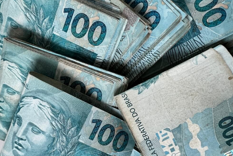 Notas de 100 reais organizadas em maços representando dinheiro disponível para saque.