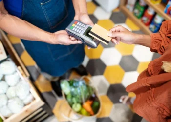 Pessoa realizando pagamento com cartão de débito, representando a utilização do cartão alimentação em um supermercado.