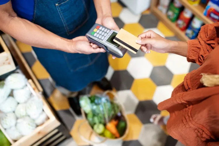 Pessoa realizando pagamento com cartão de débito, representando a utilização do cartão alimentação em um supermercado.