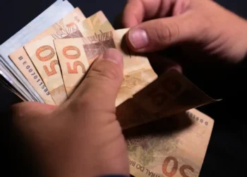 Pessoa manuseando cédulas de dinheiro de 50 reais.