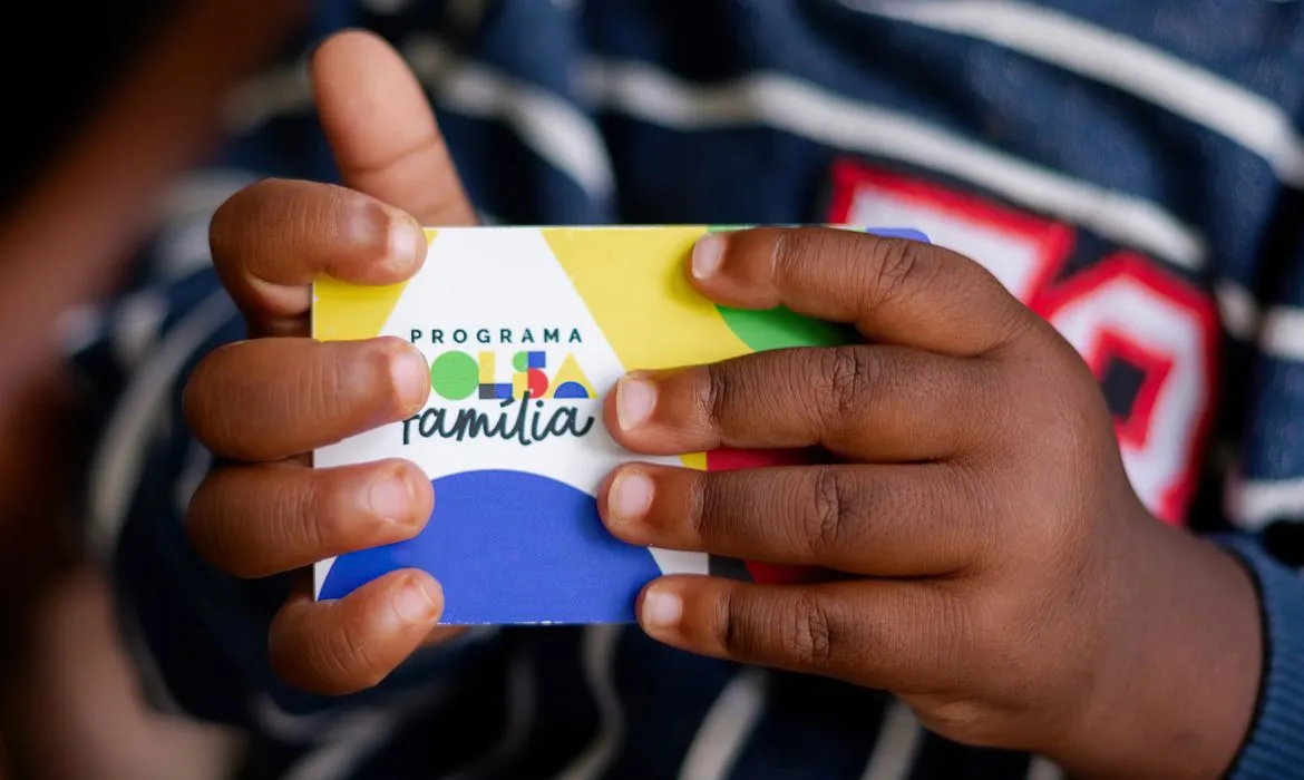 Criança segurando cartão do Bolsa Família com design colorido