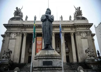 Estátua em frente à Assembleia Legislativa do Rio de Janeiro, com a fachada imponente ao fundo, representando o cenário do feriado de Tiradentes.