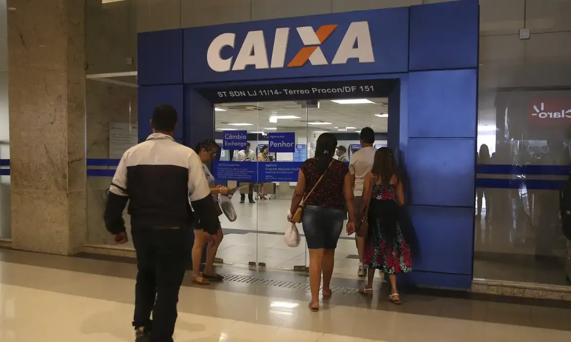 Entrada de uma agência da Caixa Econômica Federal, representando o cronograma de liberação de valores.