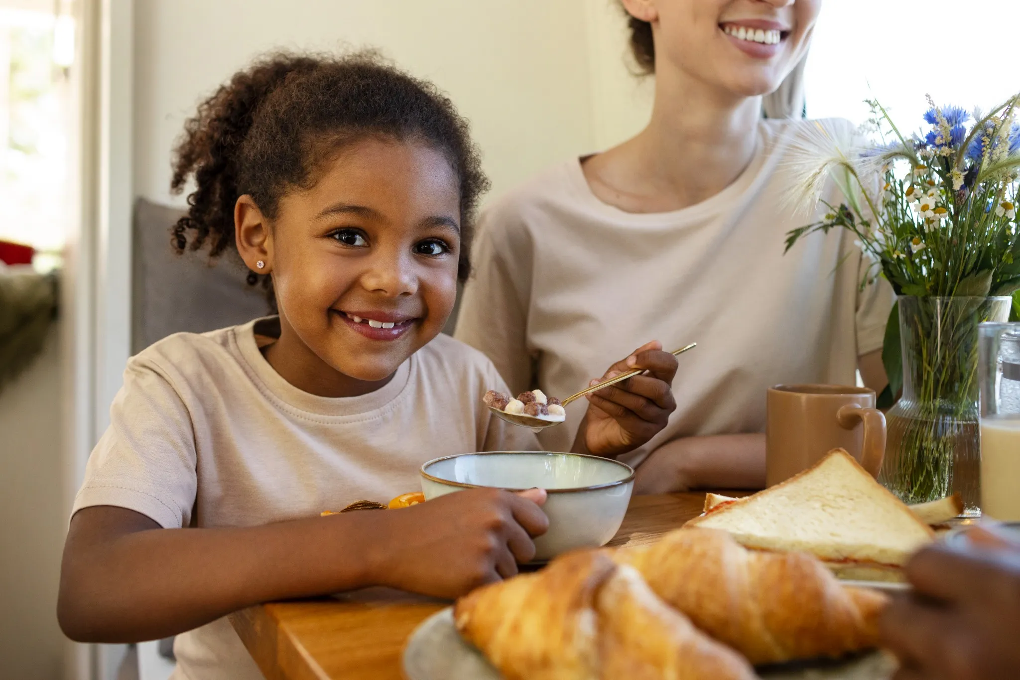 Família sorrindo durante o café da manhã, comendo juntos, representando o apoio financeiro do Caixa Tem para famílias brasileiras.