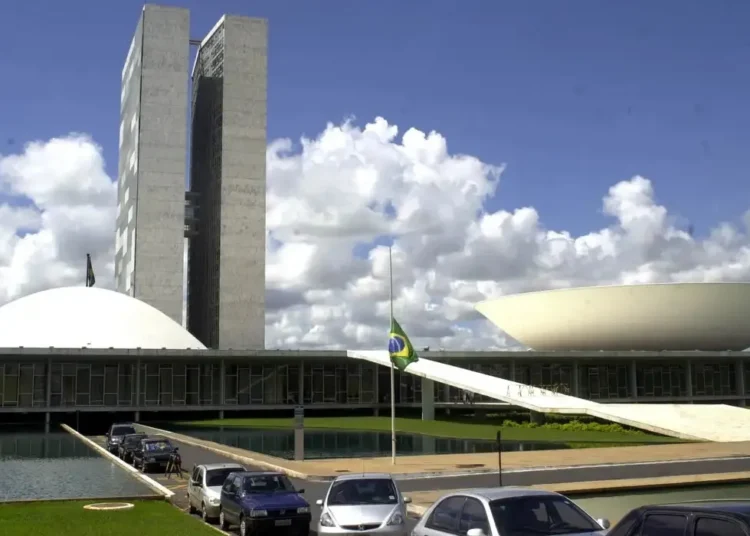 Congresso Nacional do Brasil com céu azul e nuvens ao fundo.