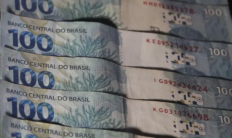 Cédulas de 100 reais empilhadas, representando o prêmio de R$ 3 mil.