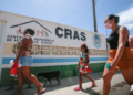 Pessoas caminhando em frente a uma unidade do CRAS sob um dia profundo.