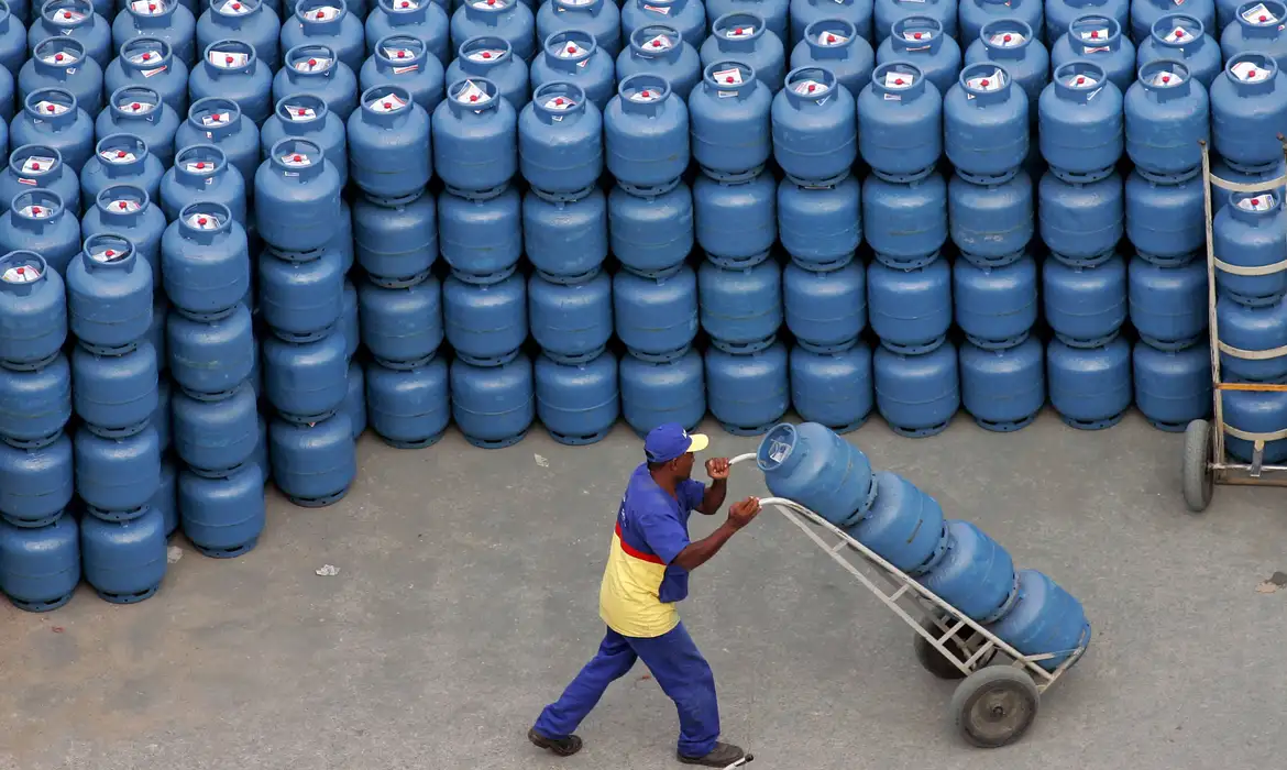 Trabalhador transportando botijões de gás de cozinha, simbolizando a distribuição do Vale-Gás para famílias de baixa renda.