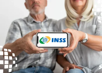 Casal de idosos segurando um celular com o logo do INSS na tela