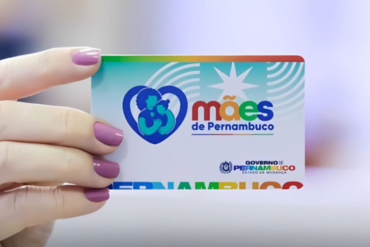 Cartão do programa Mães de Pernambuco sendo seguro por uma mão com unhas pintadas.