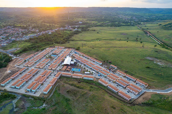 Vista aérea de um conjunto habitacional do programa Minha Casa, Minha Vida, com dezenas de casas organizadas em ruas planejadas.