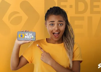 Mulher sorrindo e apontando para a tela do celular com o logo do Programa Pé-de-Meia.