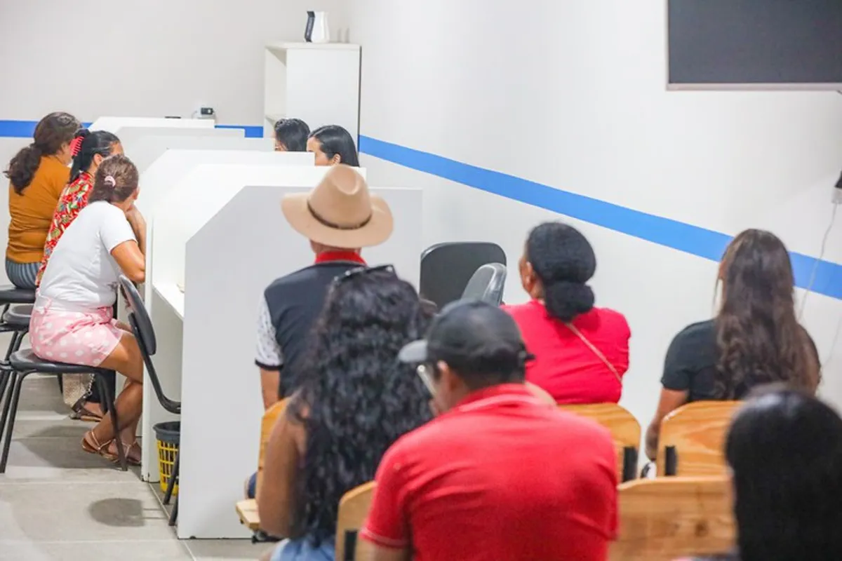 Pessoas aguardando atendimento em um ambiente com divisórias, representando o processo de atualização do Cadastro Único.